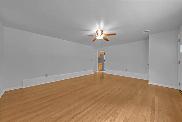 wooden floor in an empty room with a chandelier fan