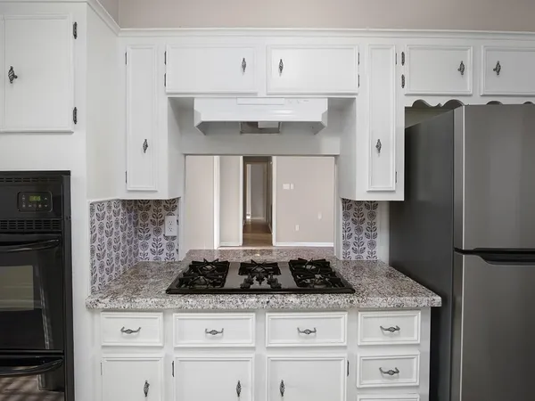 a kitchen with granite countertop a sink stove and refrigerator
