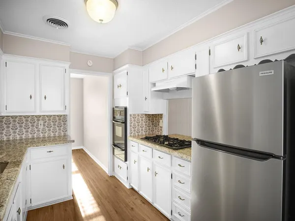 a kitchen with stainless steel appliances a refrigerator a stove and white cabinets