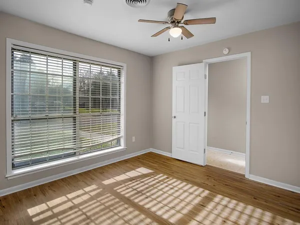 a view of empty room with wooden floor and fan