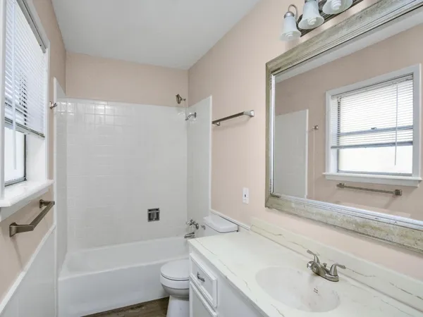 a bathroom with a bathtub shower sink vanity and toilet