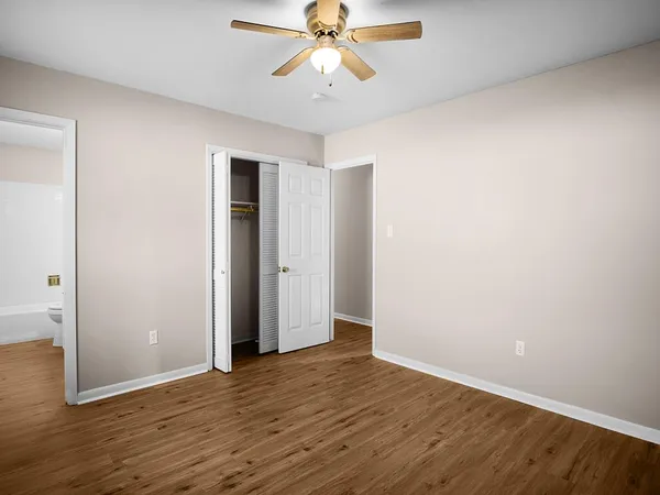 an empty room with wooden floor chandelier fan and closet area