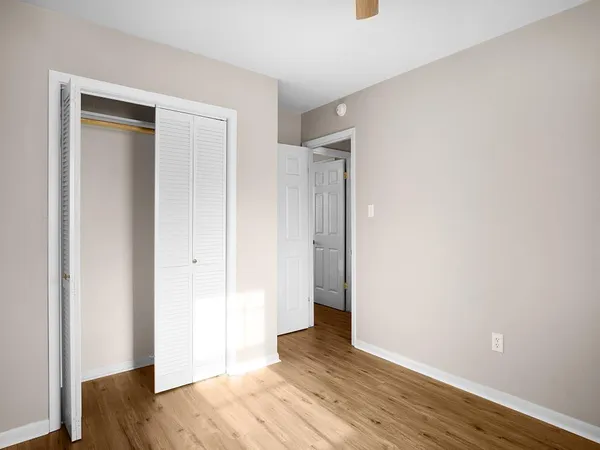 a view of an empty room with wooden floor and closet