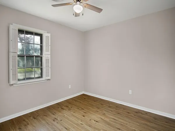 an empty room with wooden floor and windows