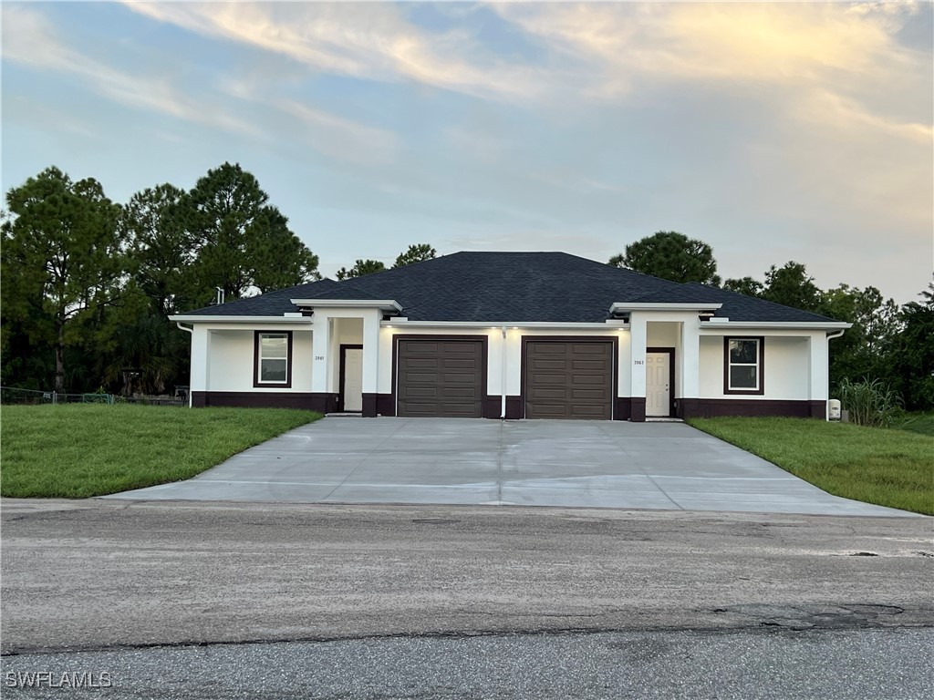 3961-3963 Sunset Road Lehigh Acres, FL 33971 - Photo 18 of 18 a front view of a house with a yard and garage