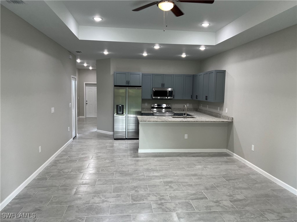 3961-3963 Sunset Road Lehigh Acres, FL 33971 - Photo 4 of 18 a large white kitchen with kitchen island a sink stainless steel appliances and cabinets