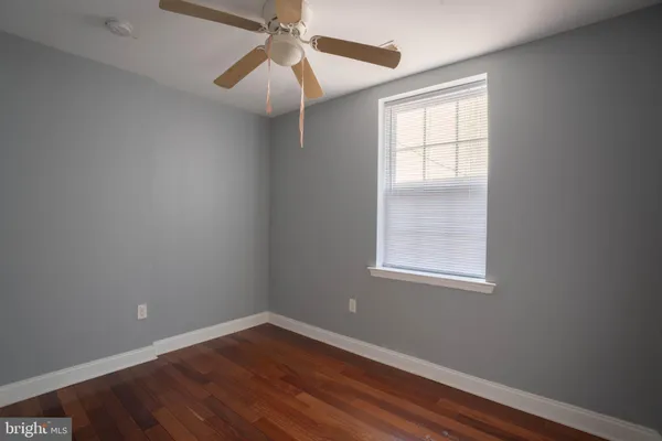 an empty room with wooden floor ceiling fan and windows