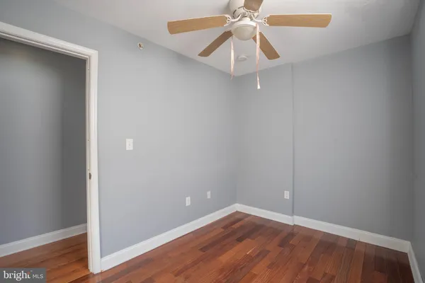 an empty room with wooden floor and fan