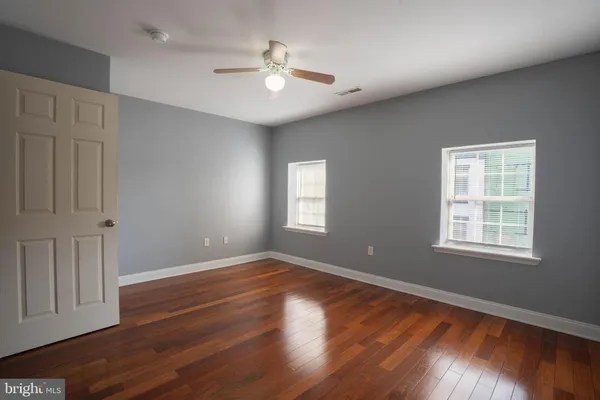 an empty room with wooden floor and windows