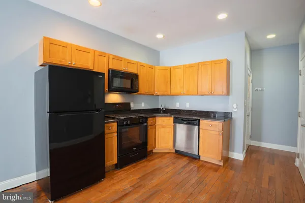 a kitchen with granite countertop wooden floors stainless steel appliances and a counter space