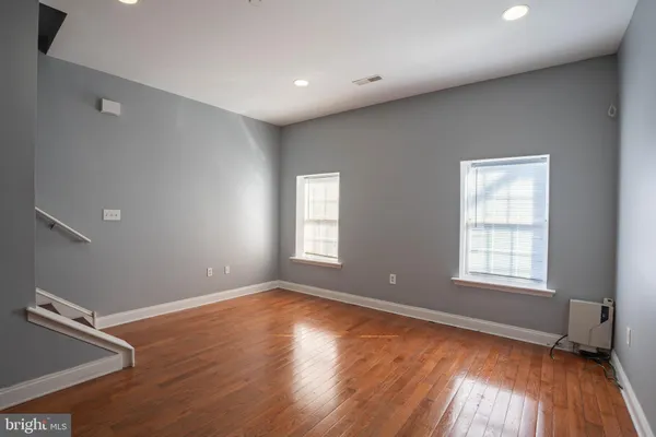 an empty room with wooden floor and windows