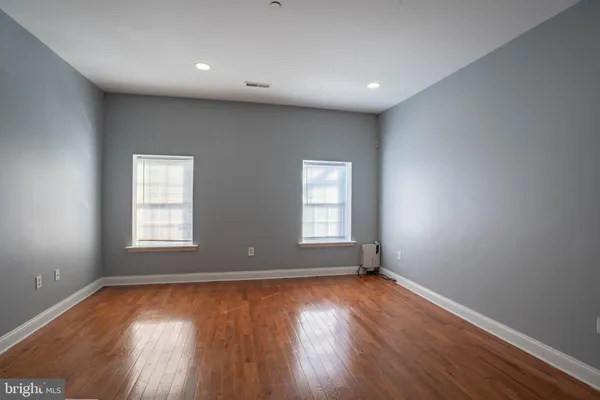 an empty room with wooden floor and windows