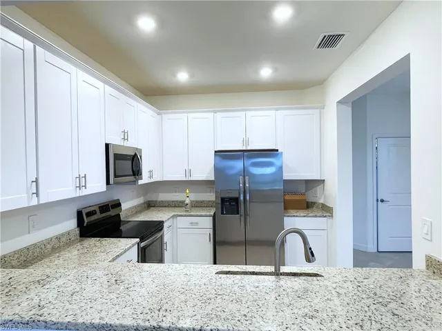 a kitchen with stainless steel appliances granite countertop a refrigerator a stove a sink and a microwave