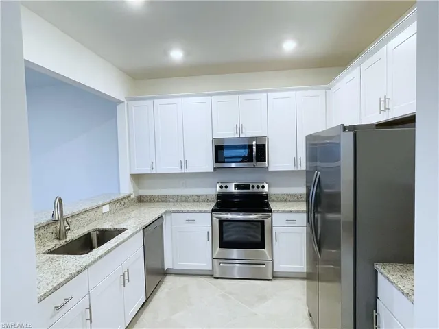 a kitchen with stainless steel appliances granite countertop a refrigerator sink and stove