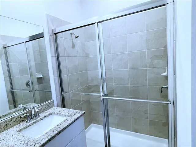 a bathroom with a granite countertop sink a shower and a mirror