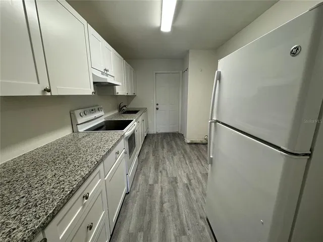 a kitchen with granite countertop a refrigerator and a sink