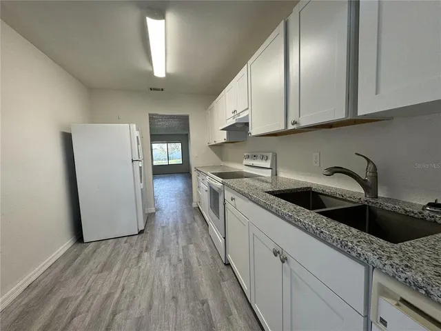 a kitchen with granite countertop white cabinets and white appliances