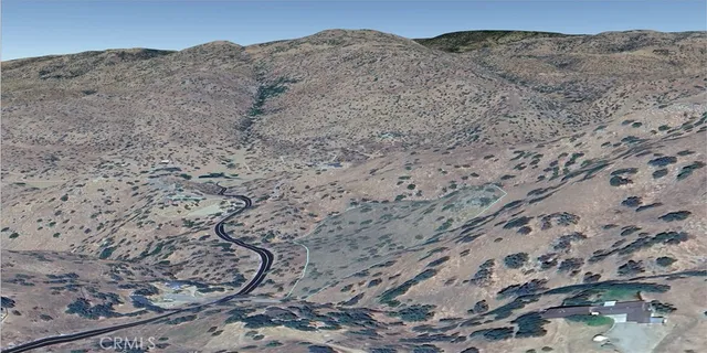 a view of a dry yard with mountains in the background