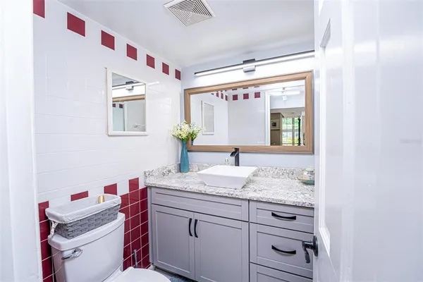 a bathroom with a granite countertop sink mirror vanity and toilet