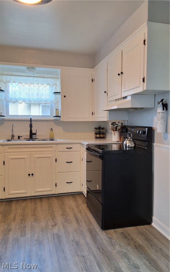 236 Bowland Road Mansfield, OH 44907 - Photo 16 of 34 Kitchen featuring white cabinetry with black hardware, a black electric range, a stainless steel sink with a black faucet, light countertops, and wood-finish flooring