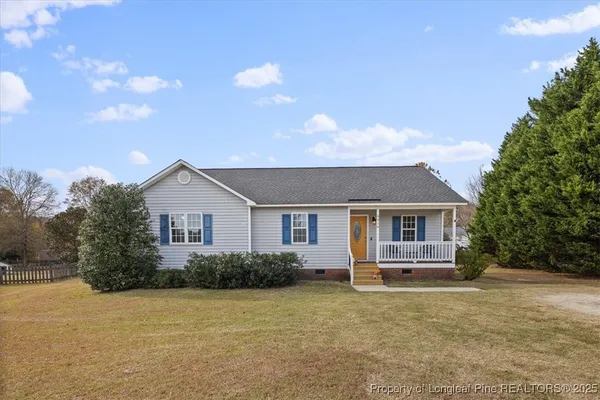 a front view of house with yard and trees in the background