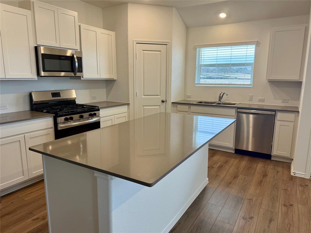 373 Jeffers Kyle, TX 78640 - Photo 7 of 26 Kitchen featuring white cabinets, stainless steel appliances, dark wood-style flooring, a center island, and recessed lighting