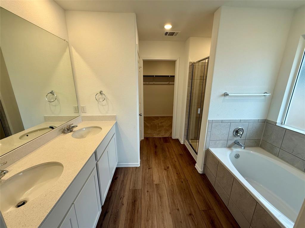 373 Jeffers Kyle, TX 78640 - Photo 9 of 26 Full bath with a garden tub, double vanity, a stall shower, dark wood-style flooring, and a walk in closet