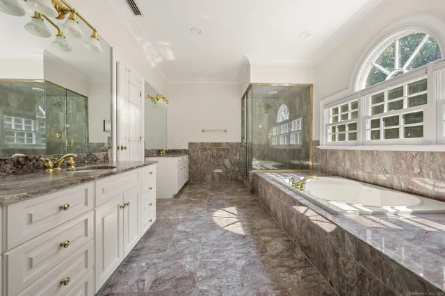 a large bathroom with a granite countertop double vanity sink a mirror a bathtub and next to a window