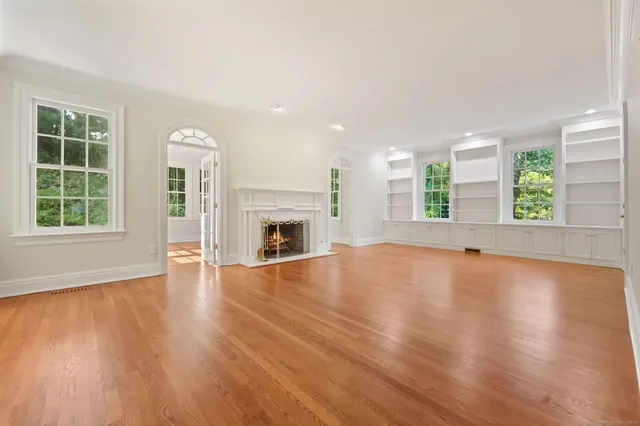 an empty room with windows fireplace and wooden floor