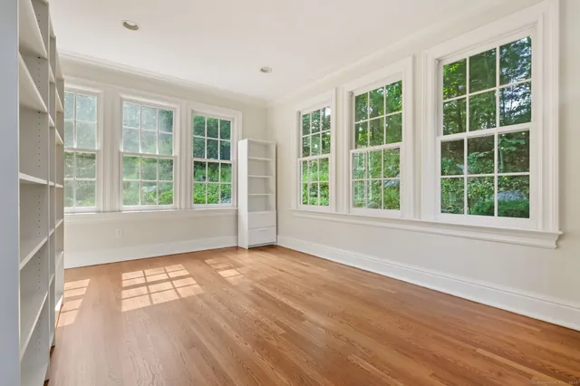 a view of an empty room with wooden floor and windows