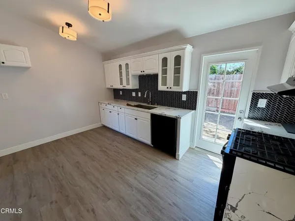 a kitchen with stainless steel appliances a stove a sink dishwasher a microwave oven and a dining table with wooden floor