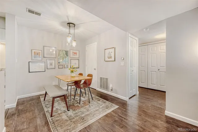 a dining room with wooden floor a chandelier a wooden table and chairs