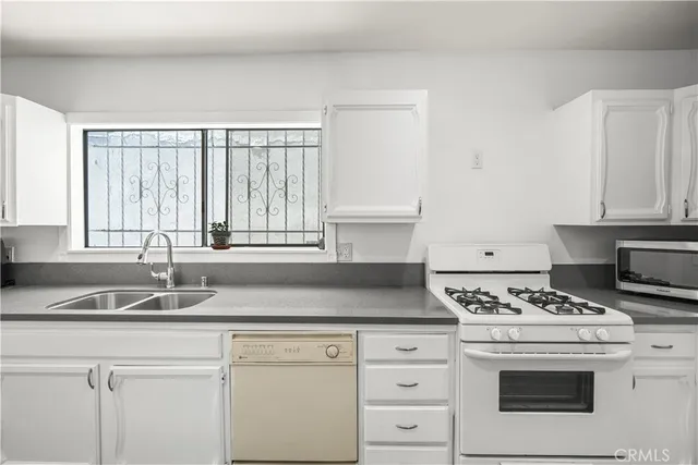 a kitchen with granite countertop white cabinets and white appliances