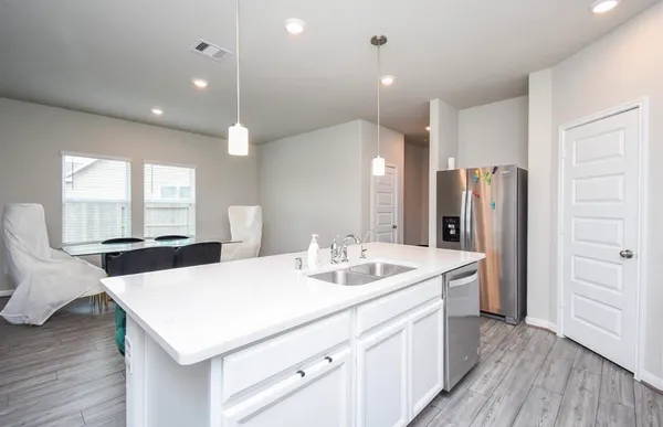 a kitchen with a sink a refrigerator and wooden floor