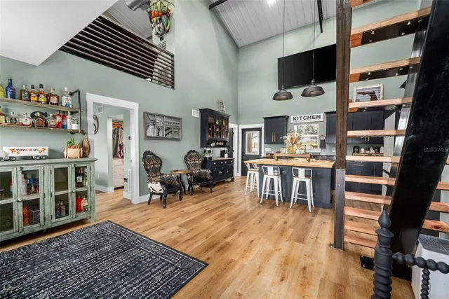 a living room with stainless steel appliances lots of furniture and wooden floor