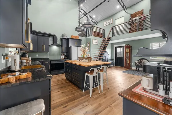 a room with stainless steel appliances kitchen island granite countertop a stove a sink dishwasher and a flat screen tv