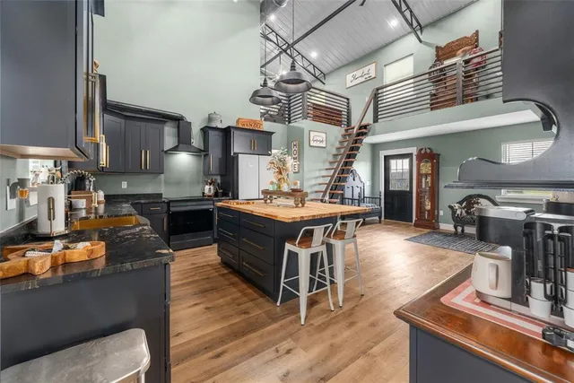 a room with stainless steel appliances kitchen island granite countertop a stove a sink dishwasher and a flat screen tv