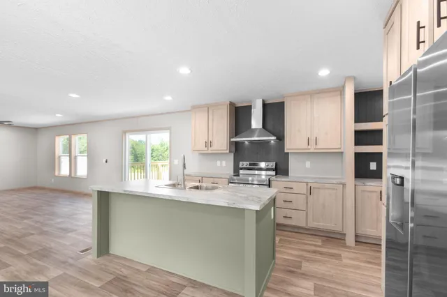 a kitchen with stainless steel appliances granite countertop a sink a stove a refrigerator cabinets and a window