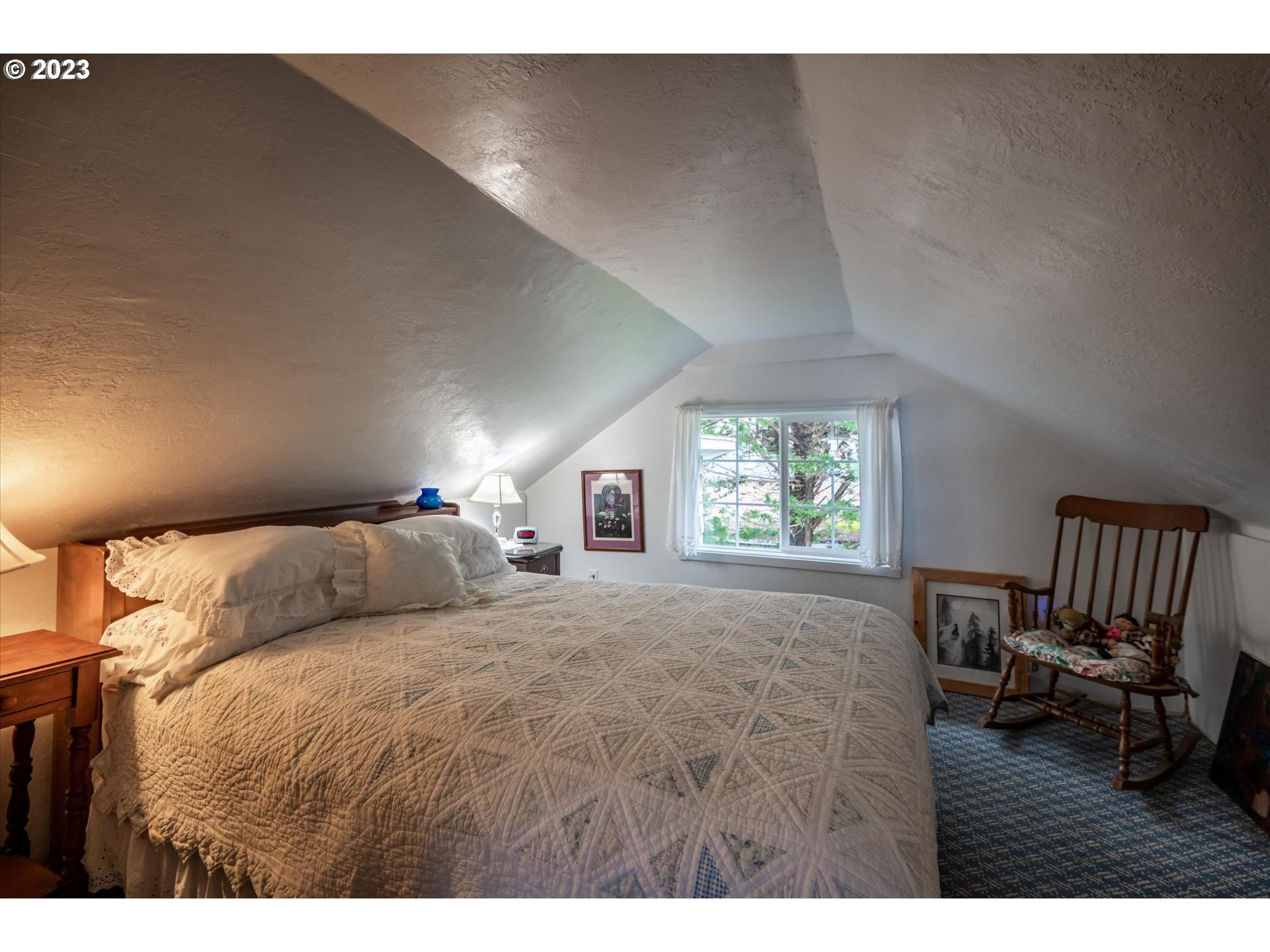 100 South 6th Street Lakeside, OR 97449 - Photo 16 of 42 a bedroom with a bed next to a window with chair