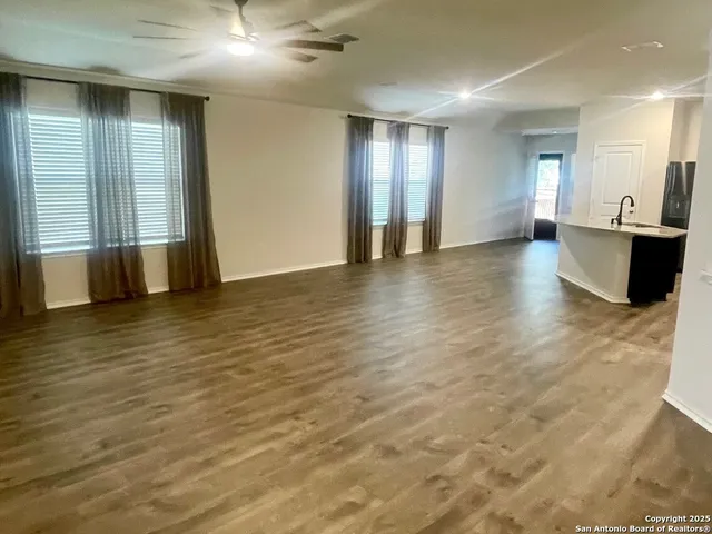a view of an empty room with wooden floor and a bathroom