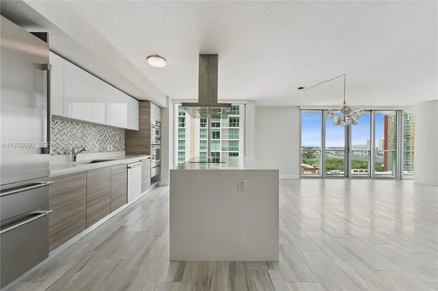 a large kitchen with kitchen island a large window a sink and appliances