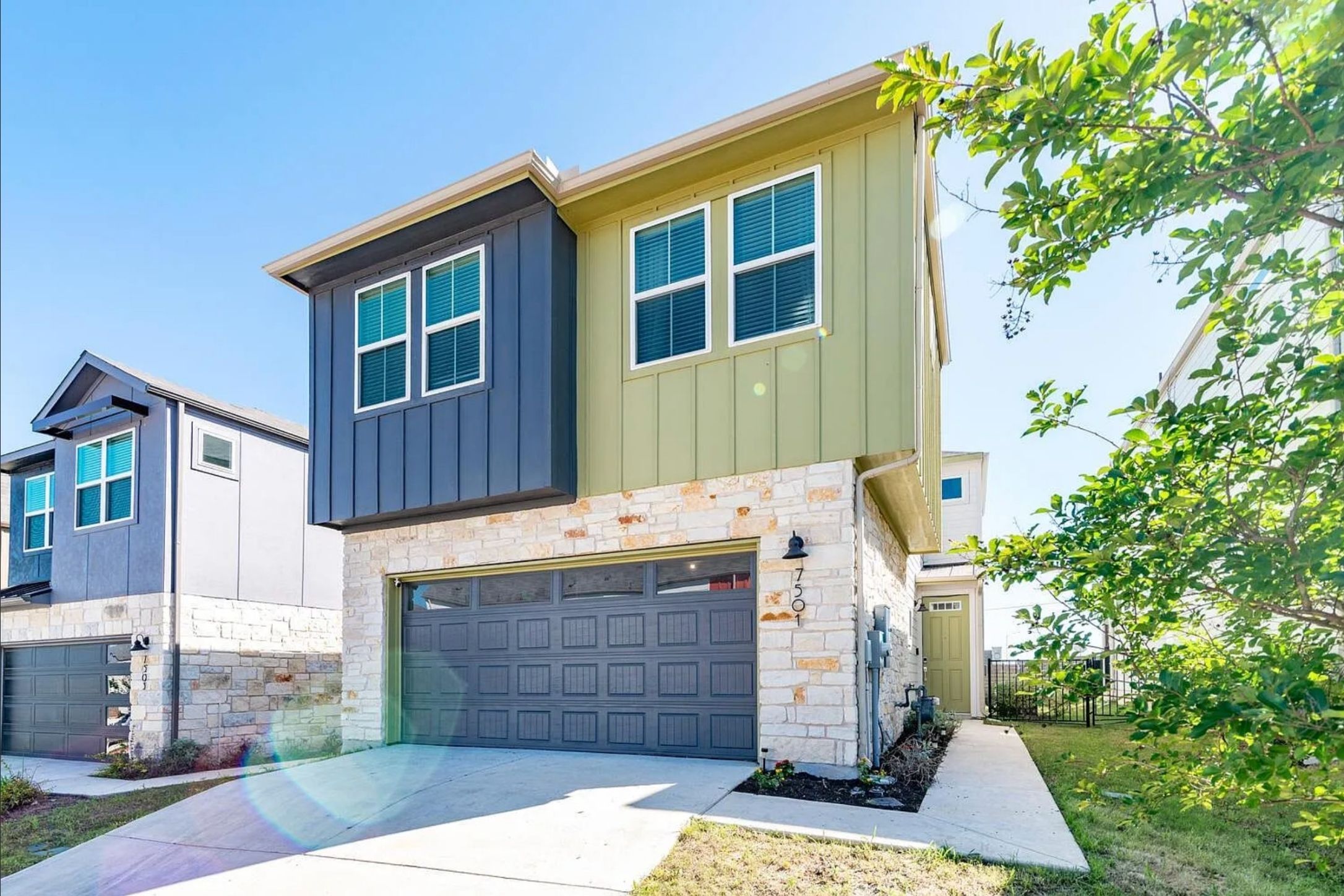 Modern multi-story exterior featuring a stone facade and vertical panel siding