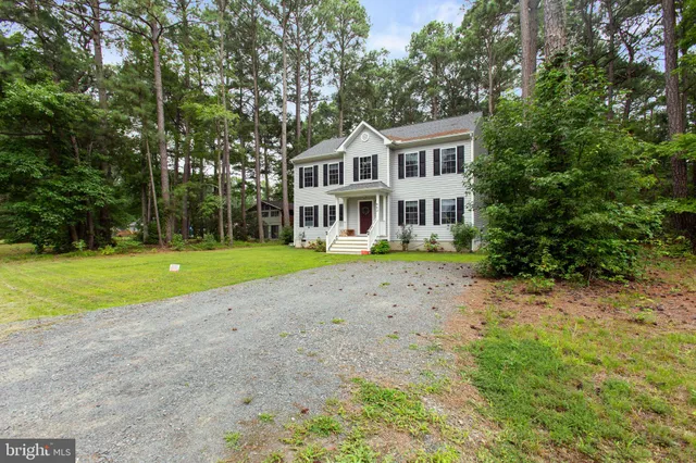 a view of a house with a big yard and large trees