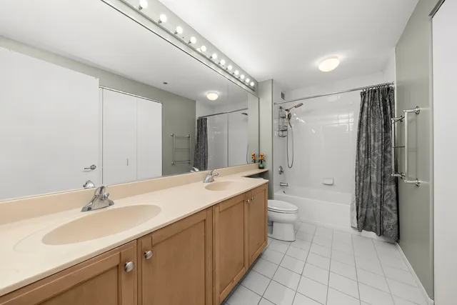 a bathroom with a double vanity sink toilet mirror and shower