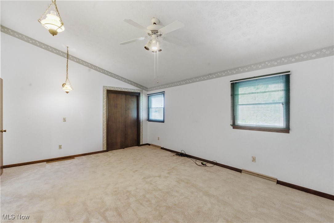 54846 Seneca Lake Road Quaker City, OH 43773 - Photo 26 of 42 Spare room featuring light colored carpet, lofted ceiling, and a ceiling fan