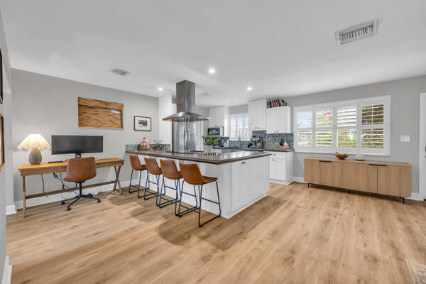 102 Pineview Road Jupiter, FL 33469 - Photo 9 of 34 a open kitchen with stainless steel appliances kitchen island granite countertop a stove a sink a refrigerator and white cabinets with wooden floor