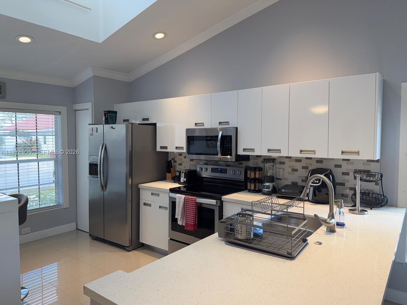 10285 Allegro Drive Boca Raton, FL 33428 - Photo 14 of 55 a kitchen with stainless steel appliances granite countertop a refrigerator a stove a sink a dining table and chairs