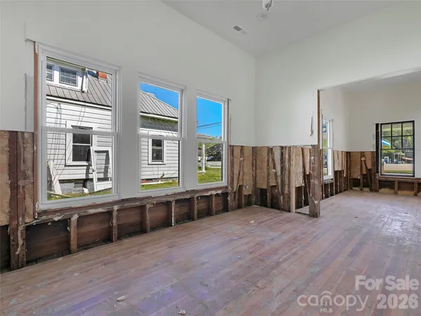 a view of an empty room with wooden floor and windows