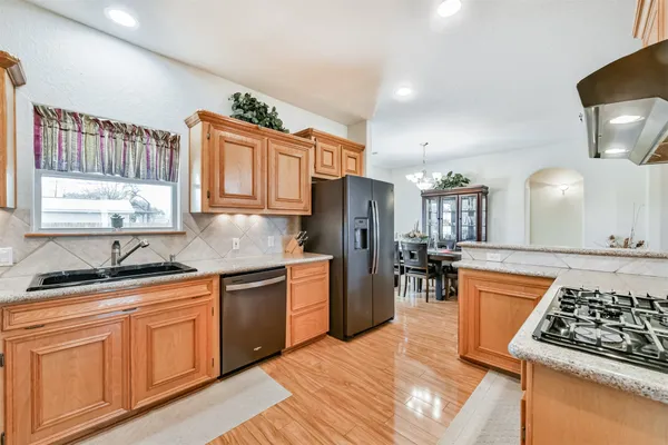 a kitchen with stainless steel appliances granite countertop a stove top oven a sink dishwasher and cabinets with wooden floor