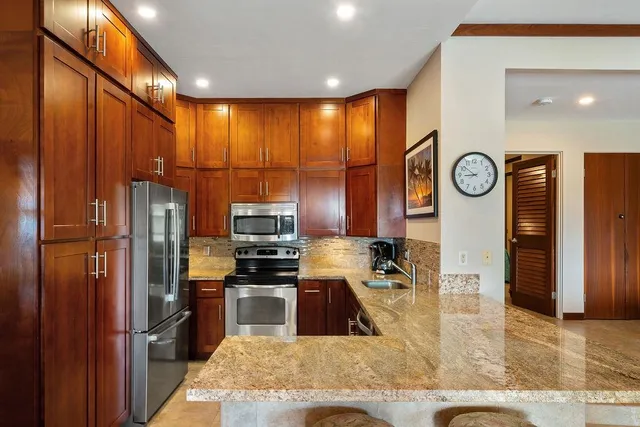 a kitchen with stainless steel appliances granite countertop a refrigerator a stove and a sink